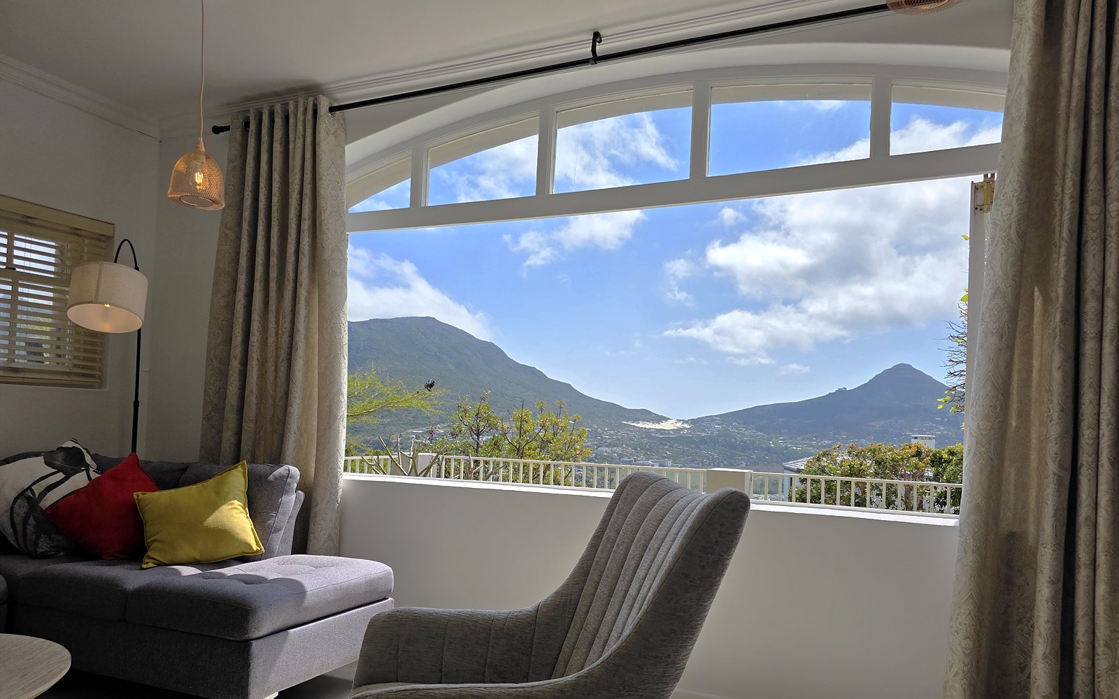Woonkamer van The Lodge met boograam en panorama over de bergen en de baai van Hout Bay