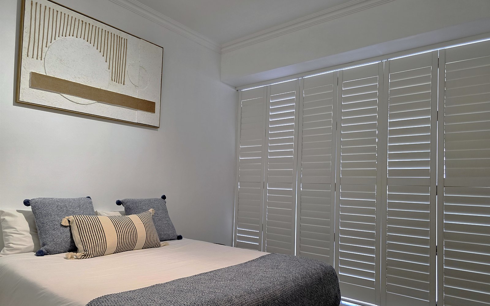 Bed van The Lodge met kunstwerk en witte shutterwand