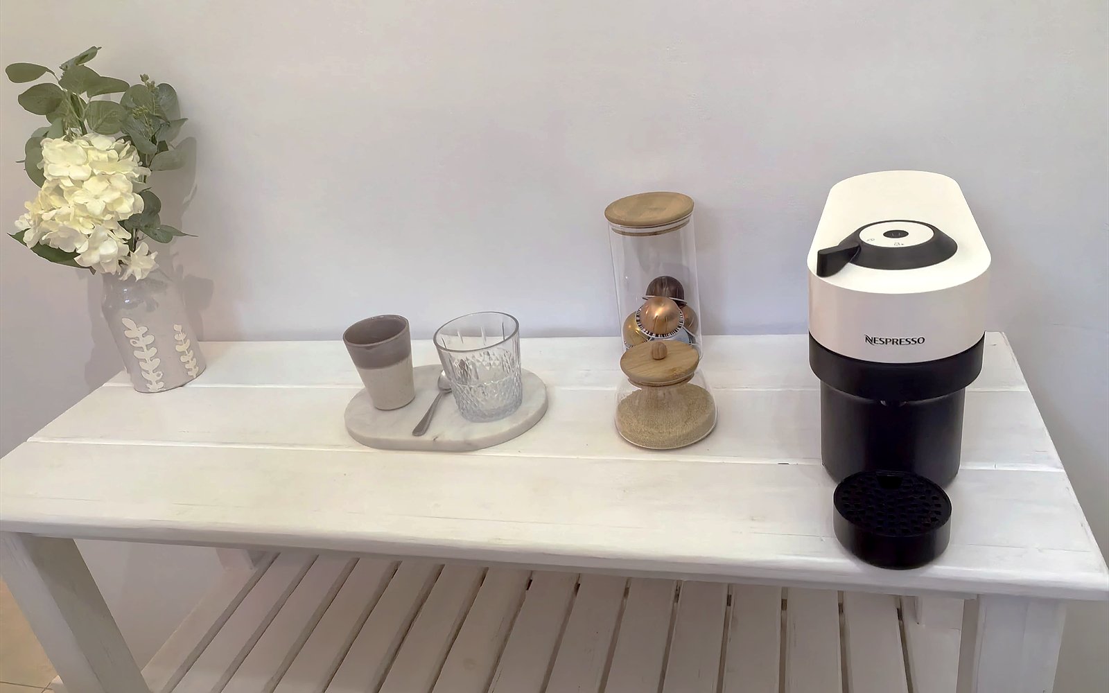 Koffiehoek van The Lodge met Nespresso-machine, kopjes en verse bloemen