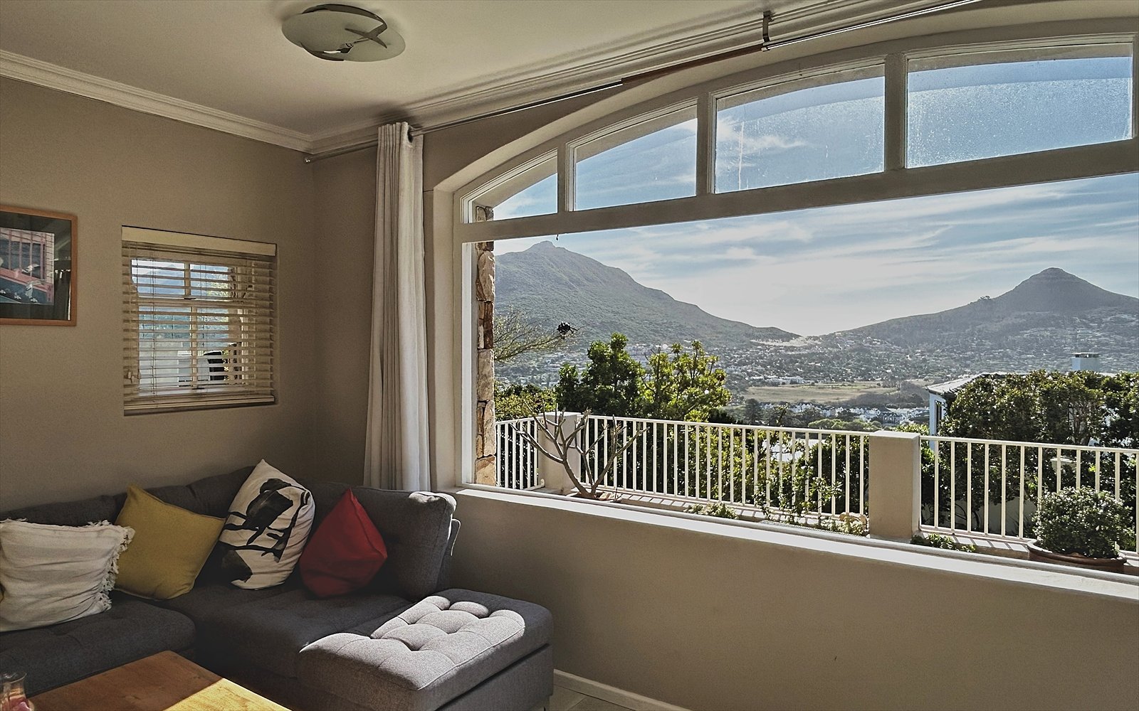 Woonkamer met hoekbank en boograam met uitzicht over Hout Bay