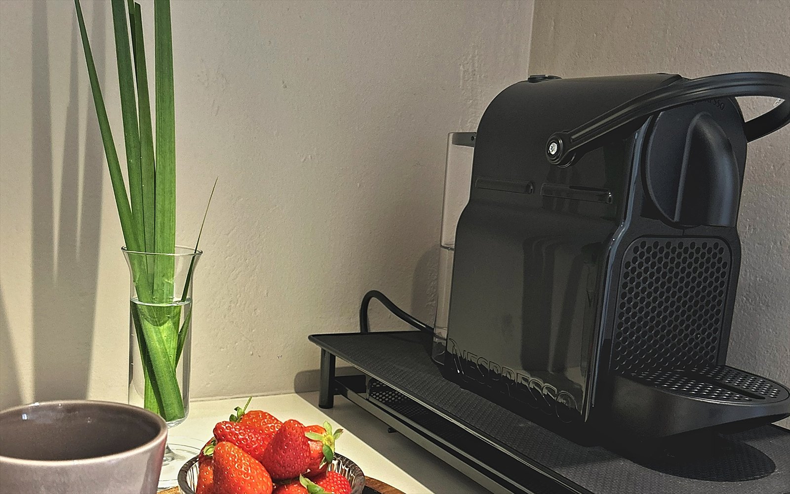 Espressoapparaat met cups, een beker en verse aardbeien