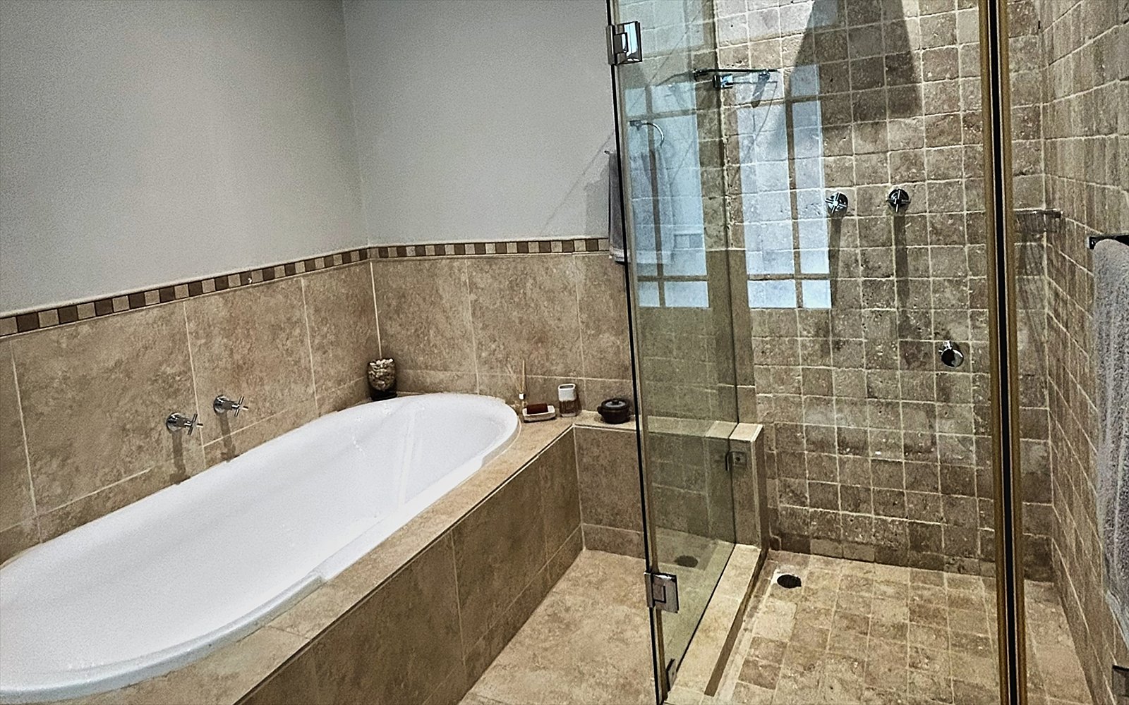 Badkamer met ligbad en inloopdouche in travertijn
