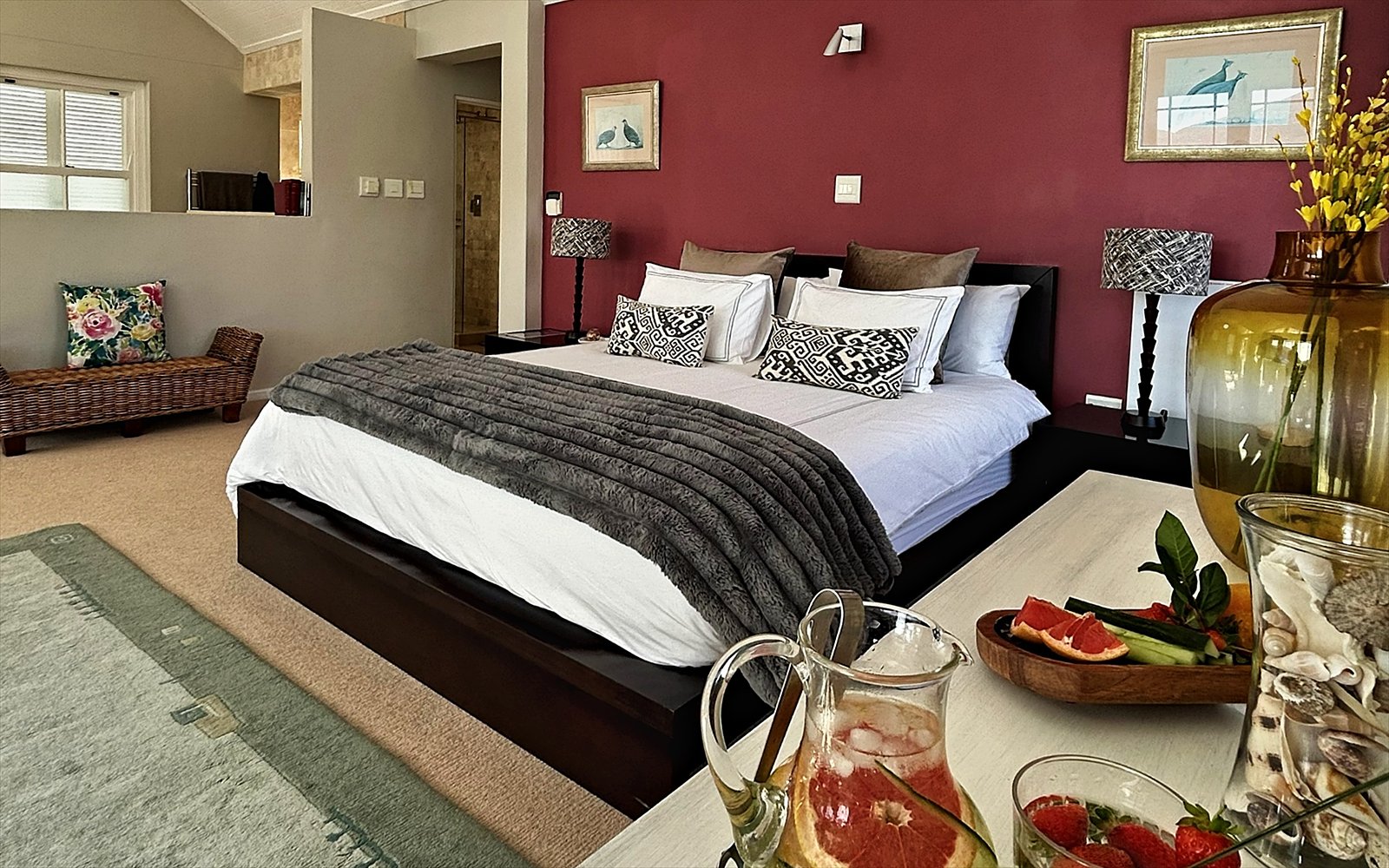 Slaapkamer van The Penthouse met hoog plafond, dieprode wand en verse verzorging op tafel