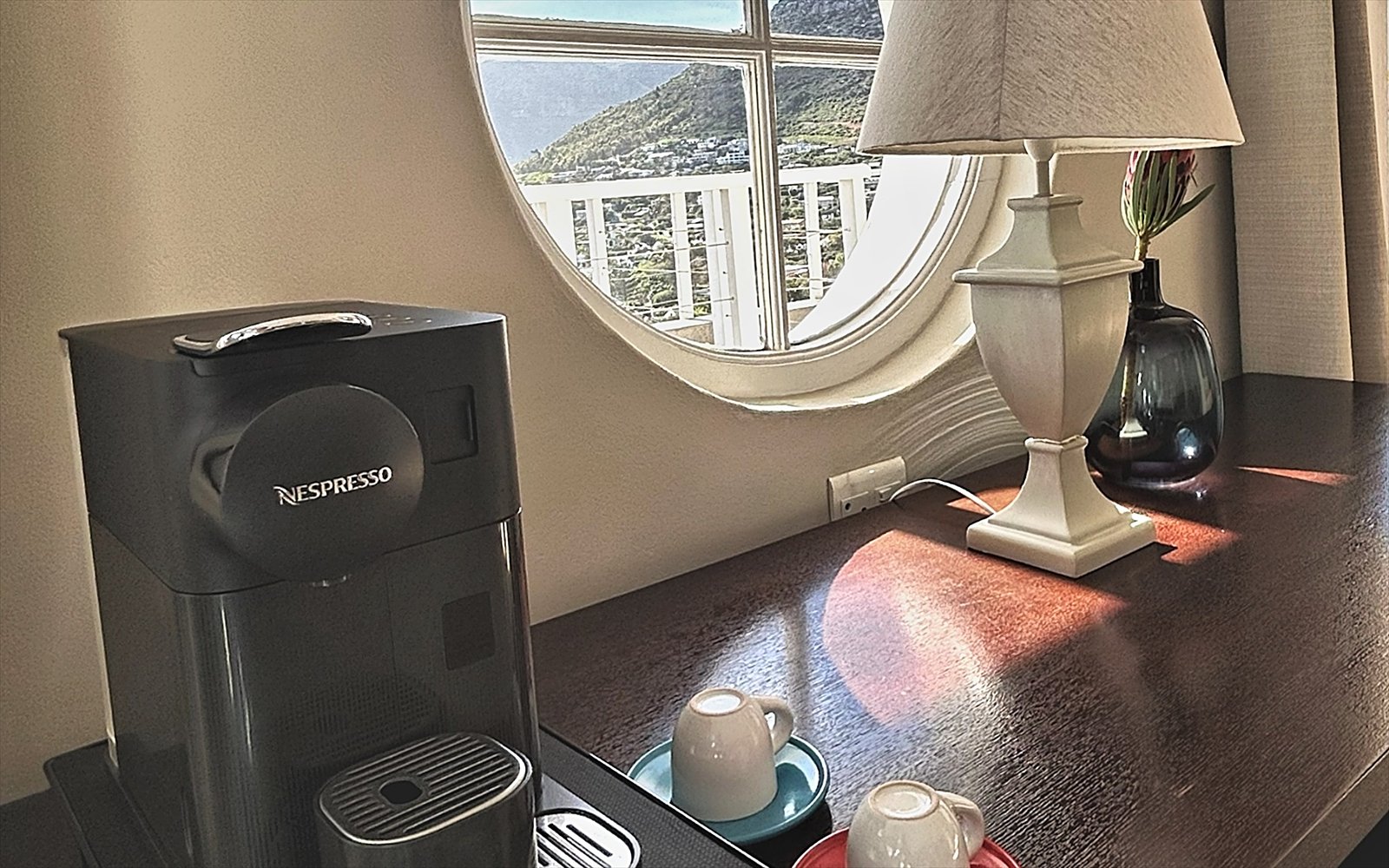 Espressoapparaat met kopjes op het dressoir, naast het ronde raam