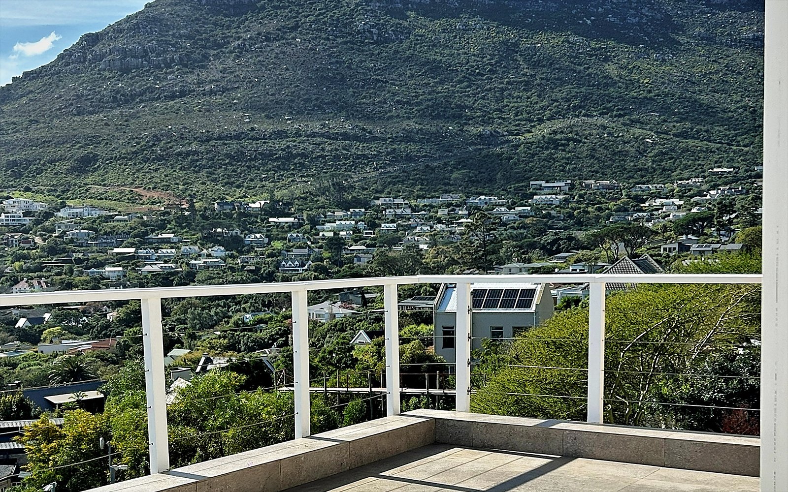 Ruim privé-zonneterras met balustrade en zicht op de berghelling
