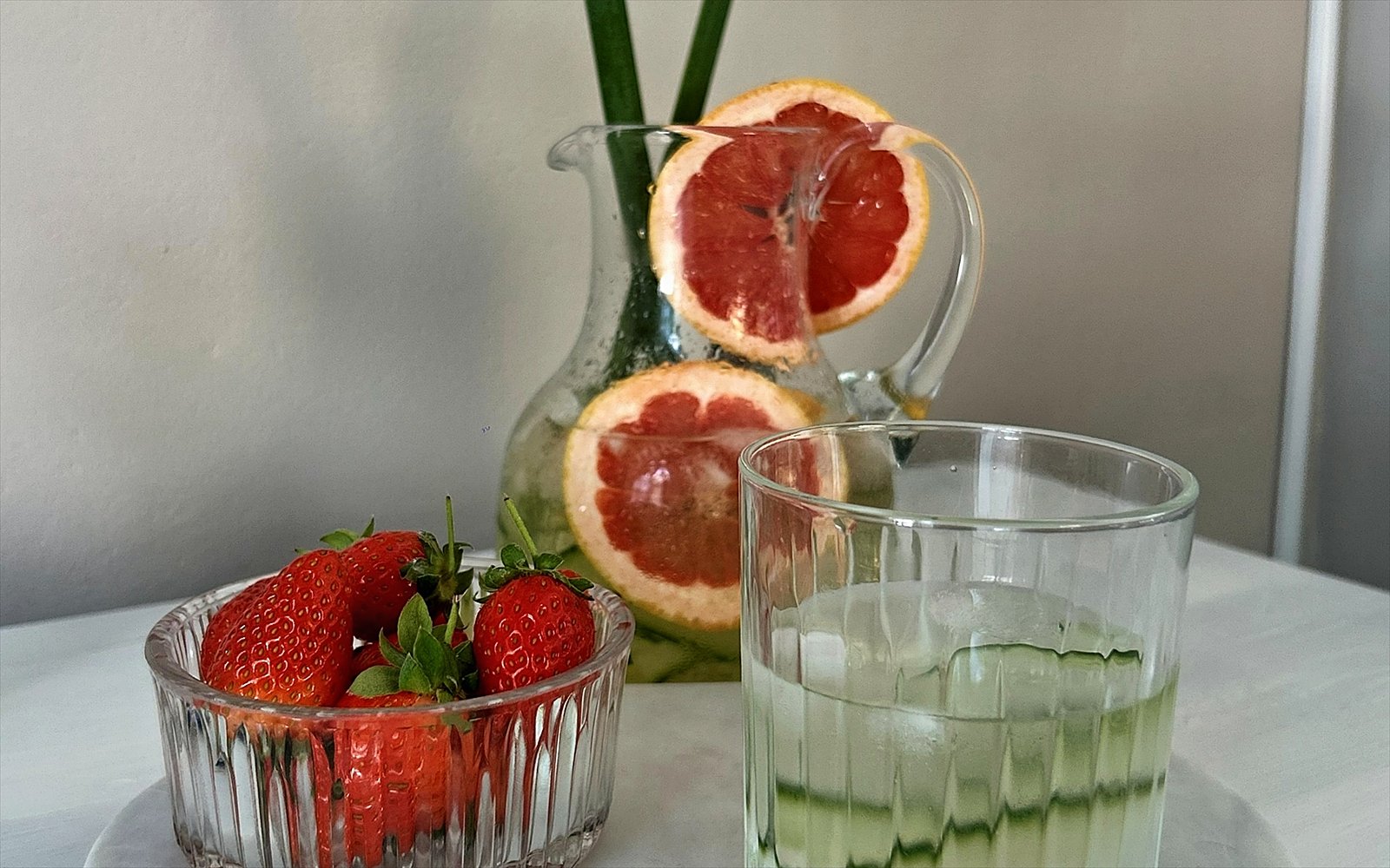 Karaf met infused water, grapefruit en aardbeien op een marmeren blad