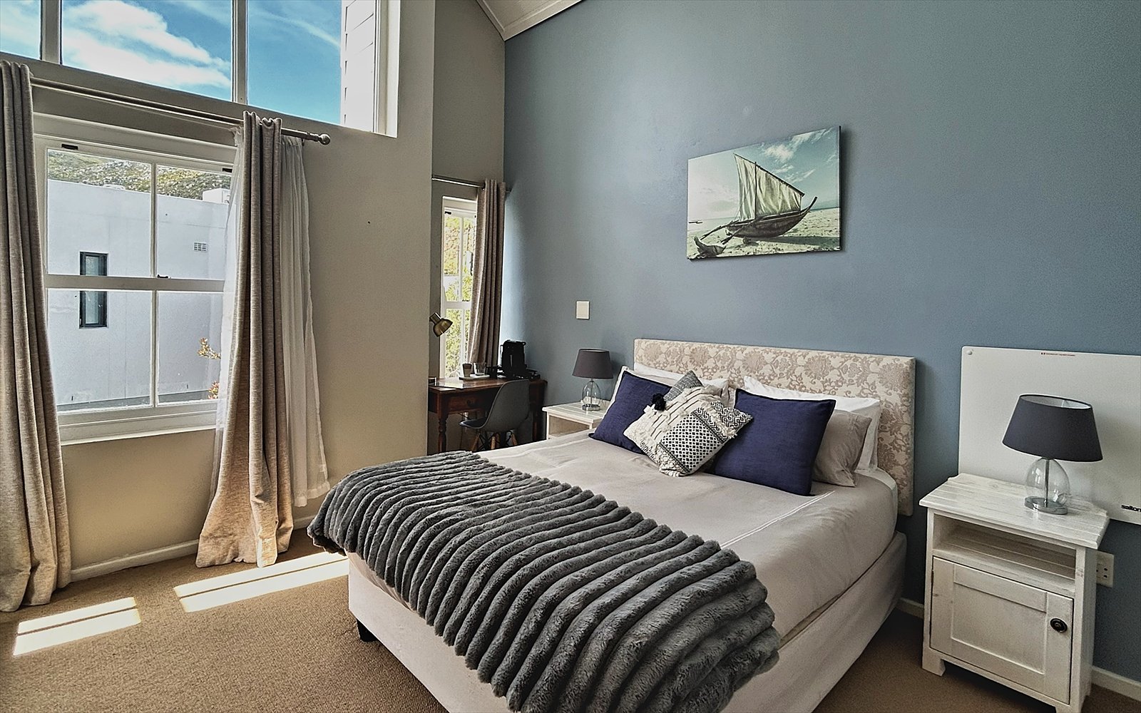 Slaapkamer van The Suite met lichtblauwe wand, hoog raam en eigen bureau